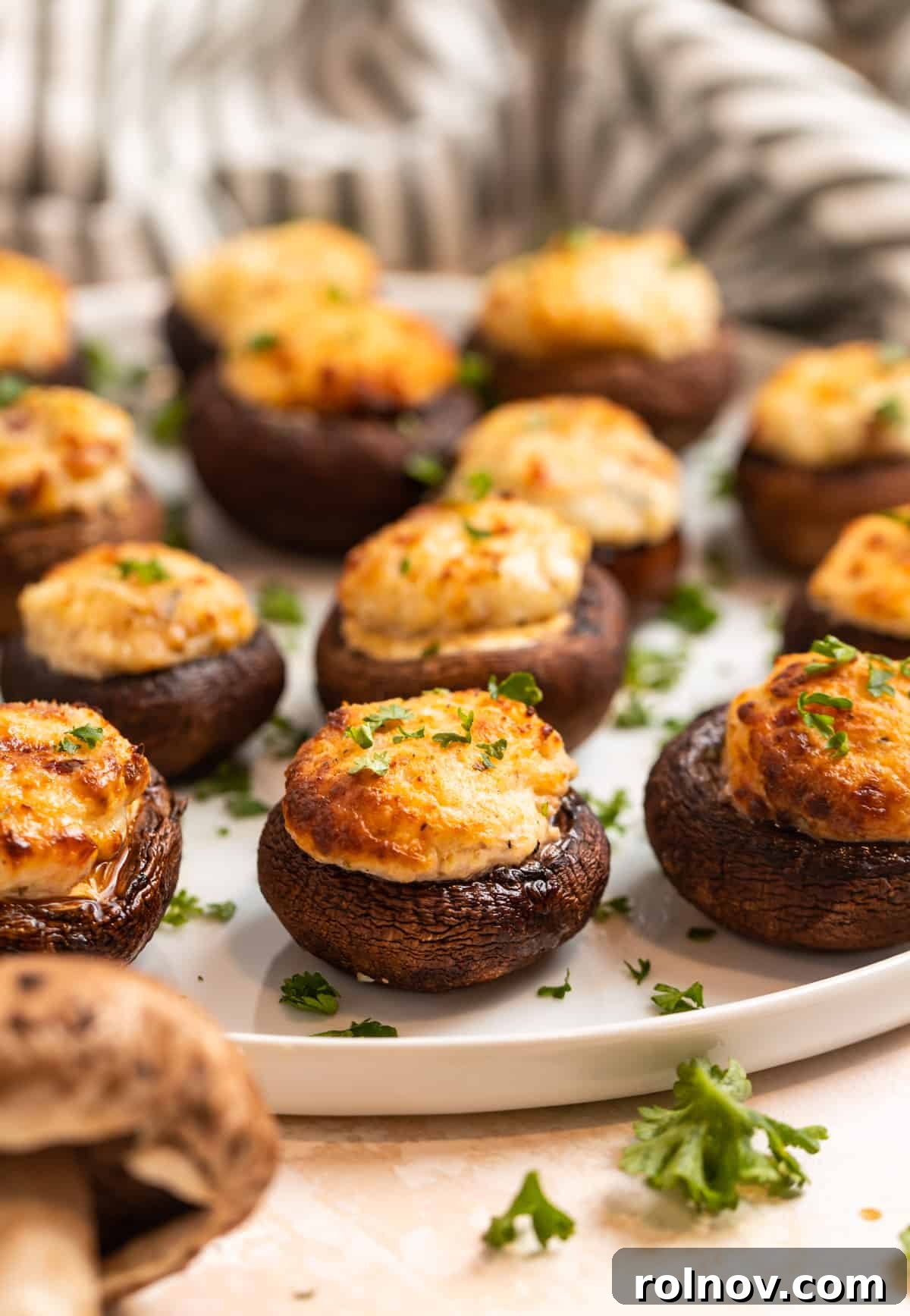 Savory Air Fryer Stuffed Mushrooms 3 Stuffed baby bella mushrooms with parsley garnish on white plate.