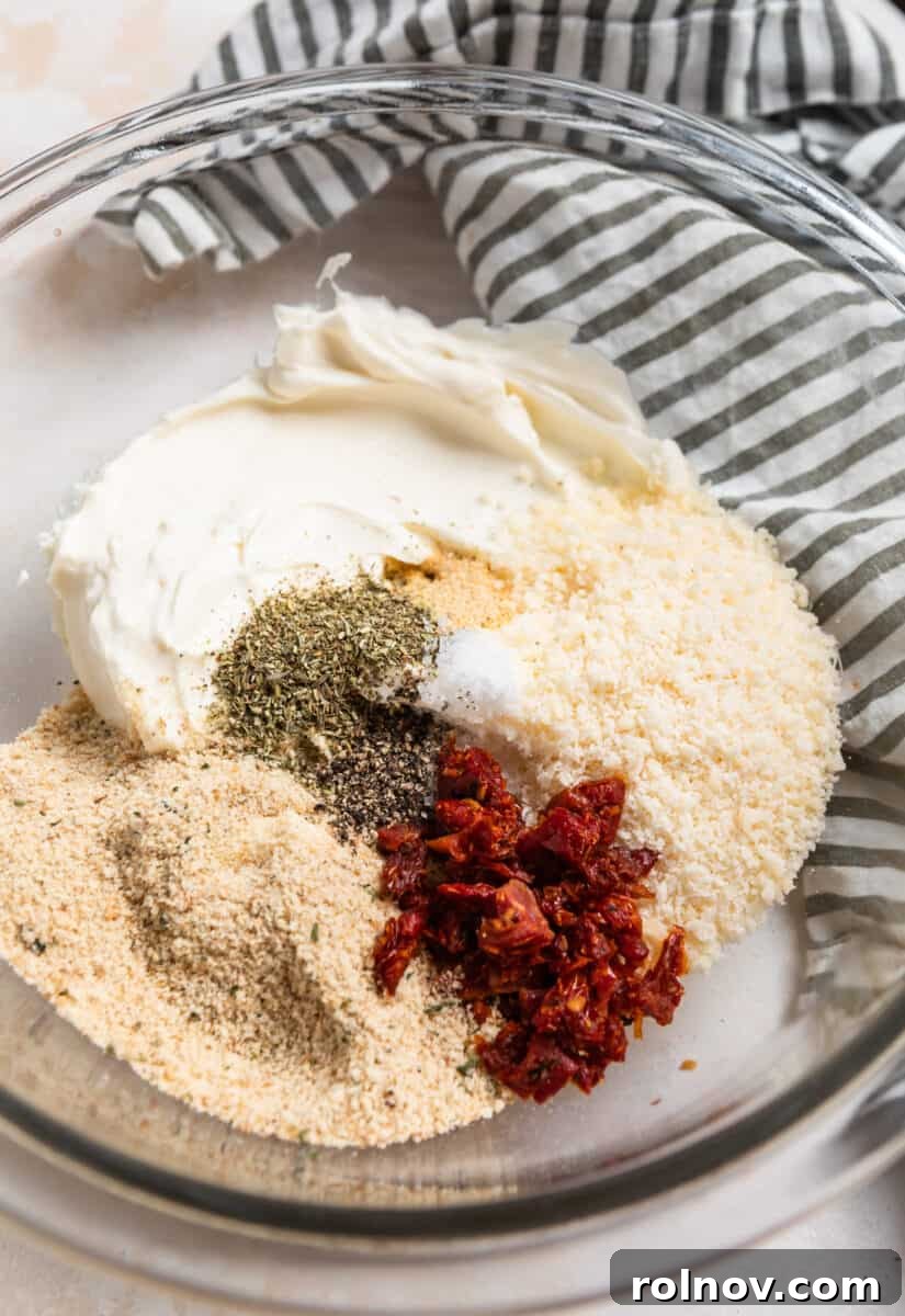 Savory Air Fryer Stuffed Mushrooms 4 Cream cheese, parmesan, sun-dried tomatoes, and other ingredients in glass mixing bowl.