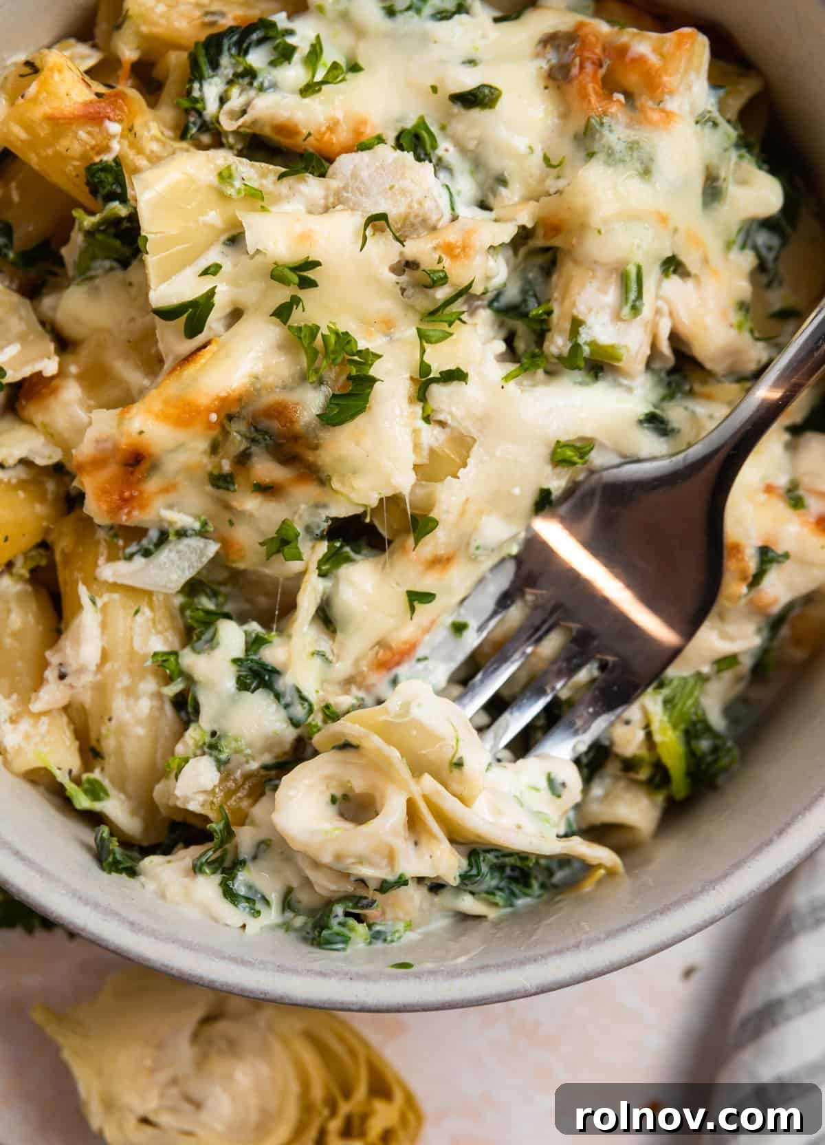 Bowl of spinach artichoke chicken casserole with forkful of the recipe.