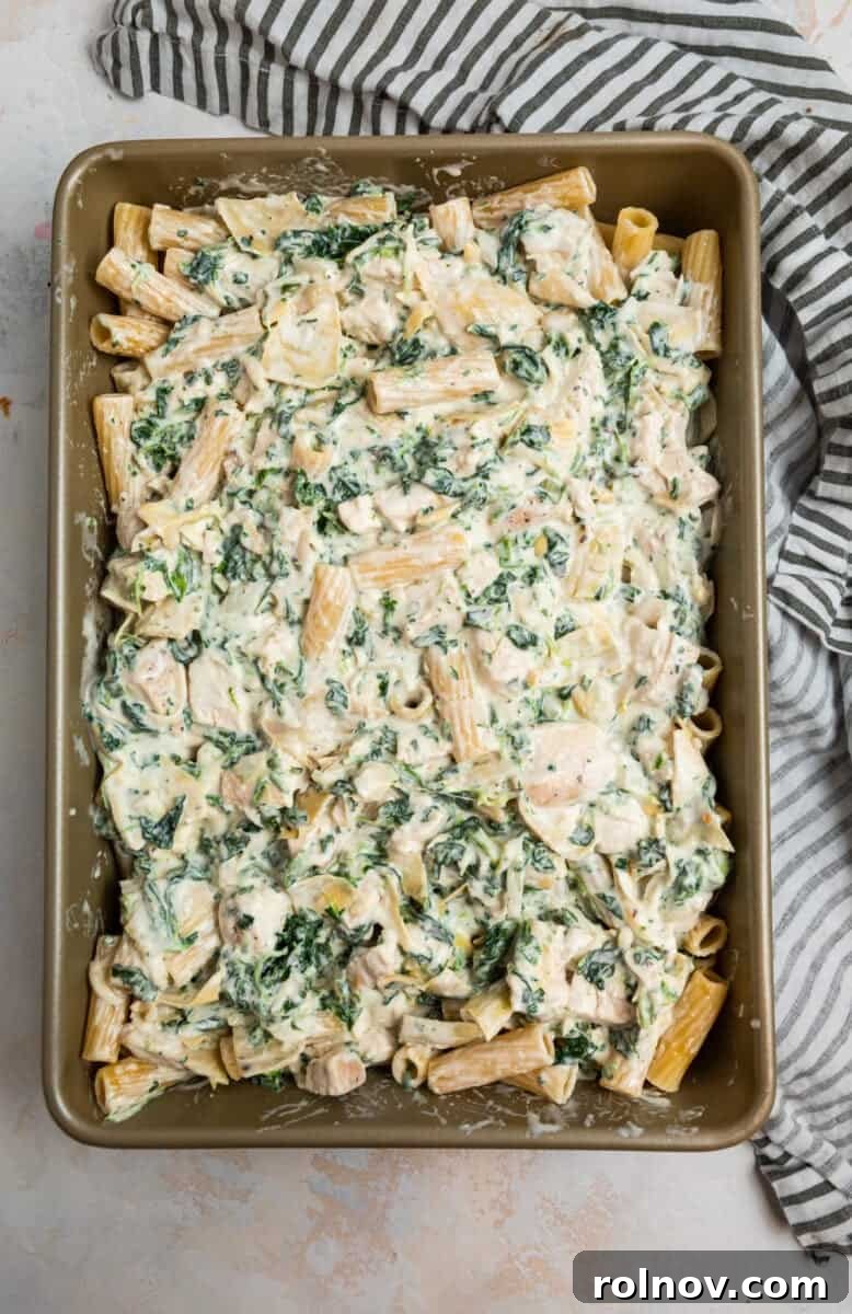 Pan with chicken, spinach and artichoke casserole before baking.