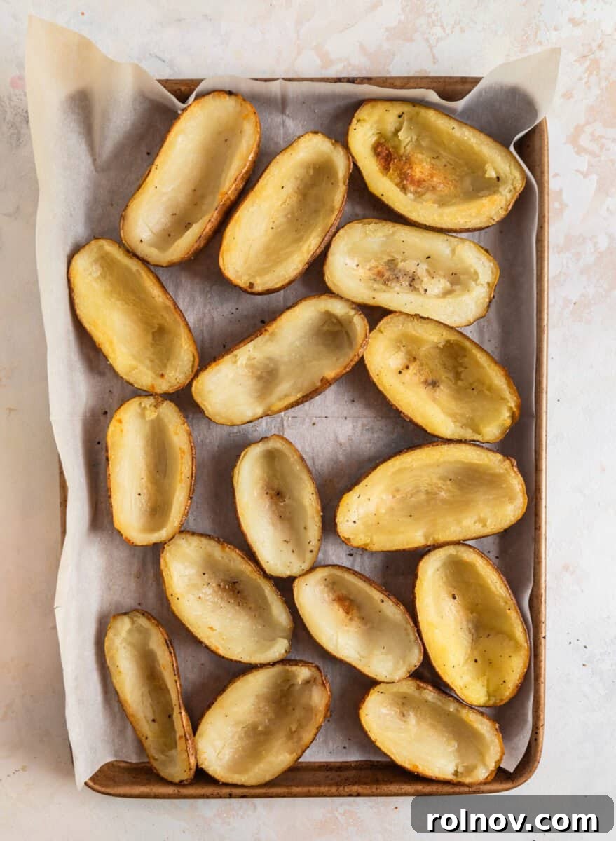 Cheesy Burger Potato Boats 7 Baked potato halves with insides scooped out on sheet pan.