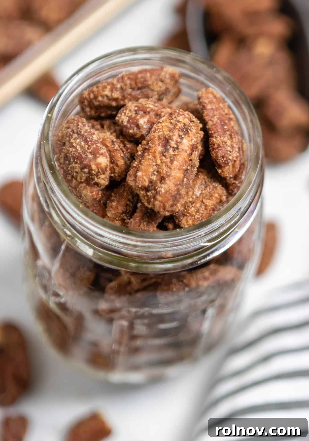 Crock Pot Pumpkin Spice Glazed Pecans 6 A charming ball jar filled with pumpkin spiced pecans, surrounded by loose pecans, highlighting their appeal as a gift.