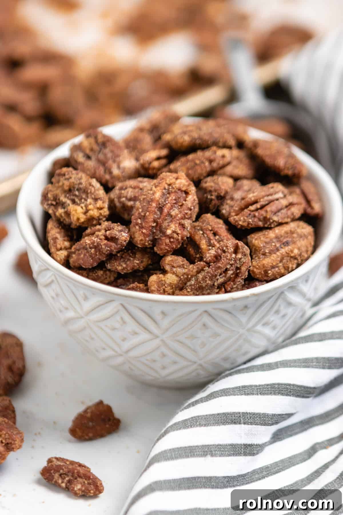 Crock Pot Pumpkin Spice Glazed Pecans 7 A simple white bowl generously filled with golden-brown candied pecans, ready for serving.