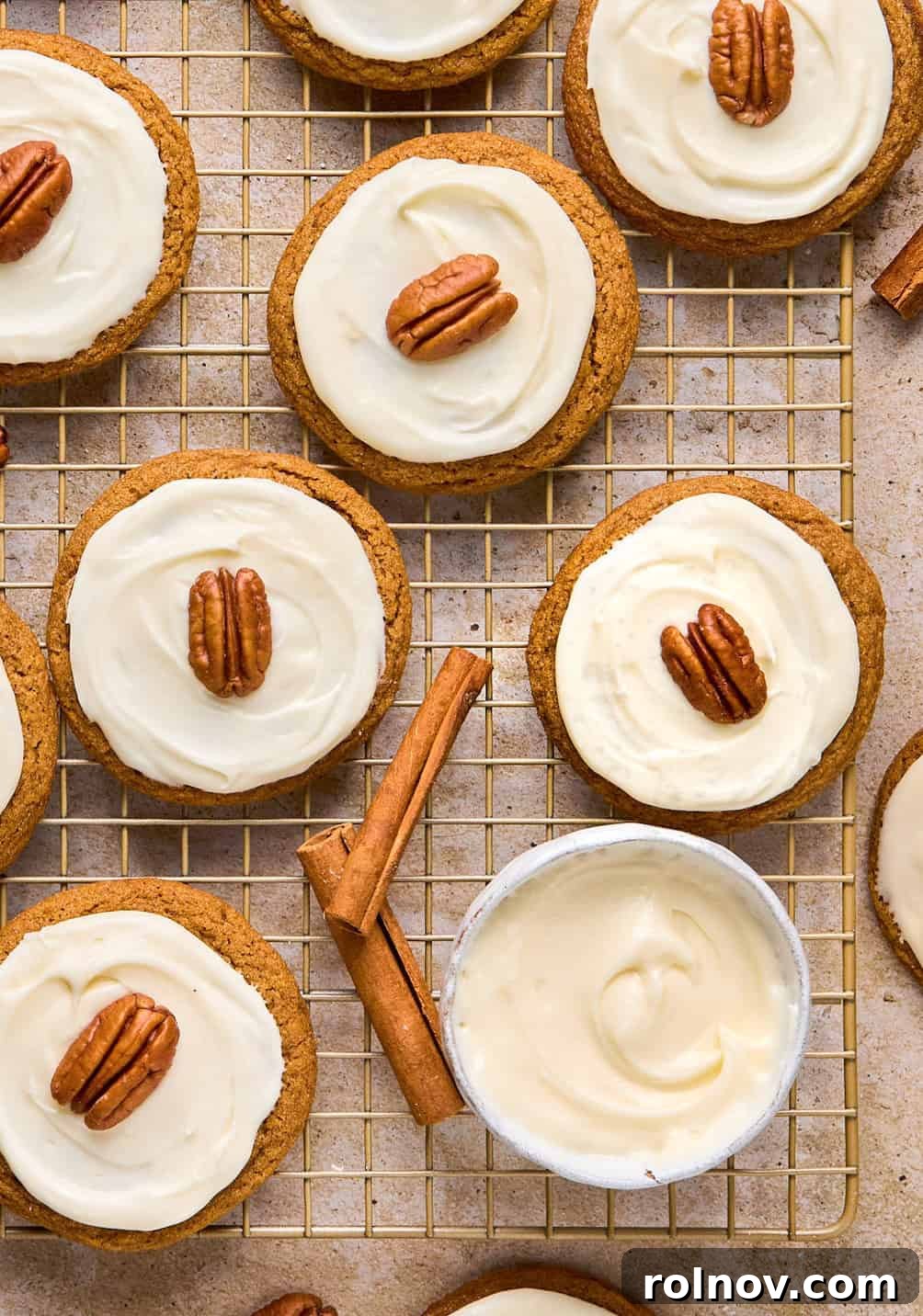 Golden Spiced Molasses Pumpkin Chews 15 Maple cream cheese frosted pumpkin spice molasses cookies on cooling rack with cinnamon sticks.