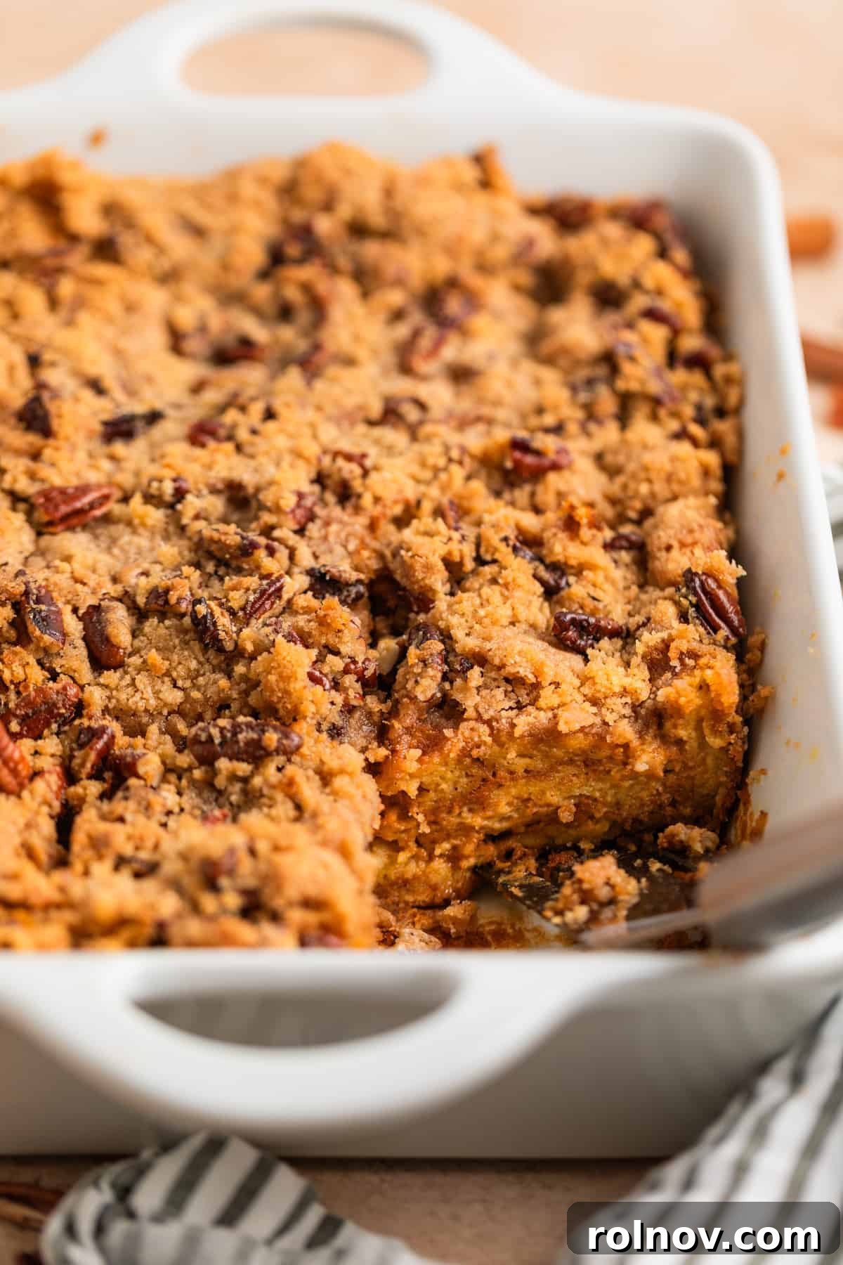 Pumpkin Spice French Toast Bake 2 Pumpkin spice French toast casserole in white dish with spatula set where one slice has been removed.