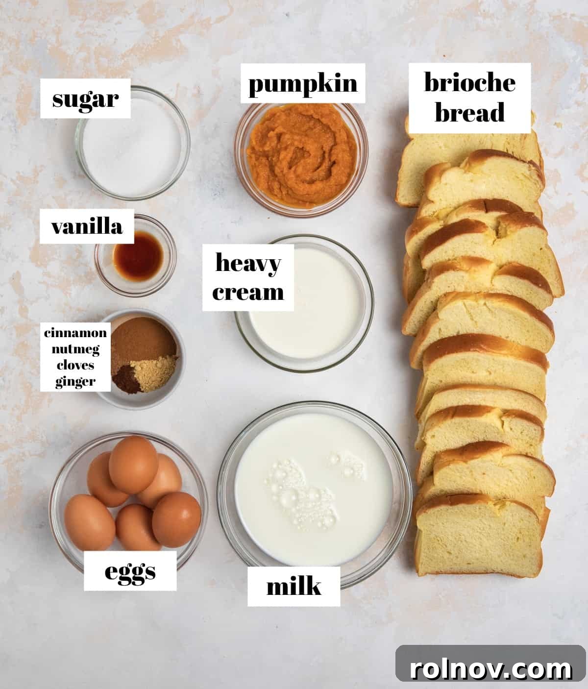 Pumpkin Spice French Toast Bake 3 Eggs, milk, cream, spices, and other ingredients labeled on counter.
