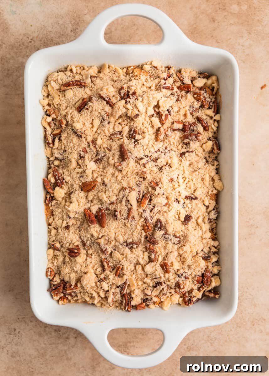 Pumpkin Spice French Toast Bake 9 Streusel pecan topping sprinkled over French toast casserole mixture in pan.
