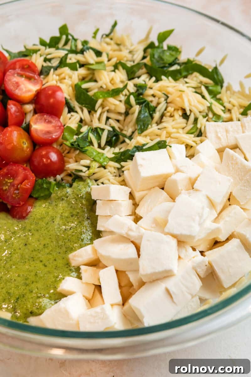 Emerald Orzo Pesto Salad 8 Orzo, tomatoes, mozzarella, and pesto in glass mixing bowl.