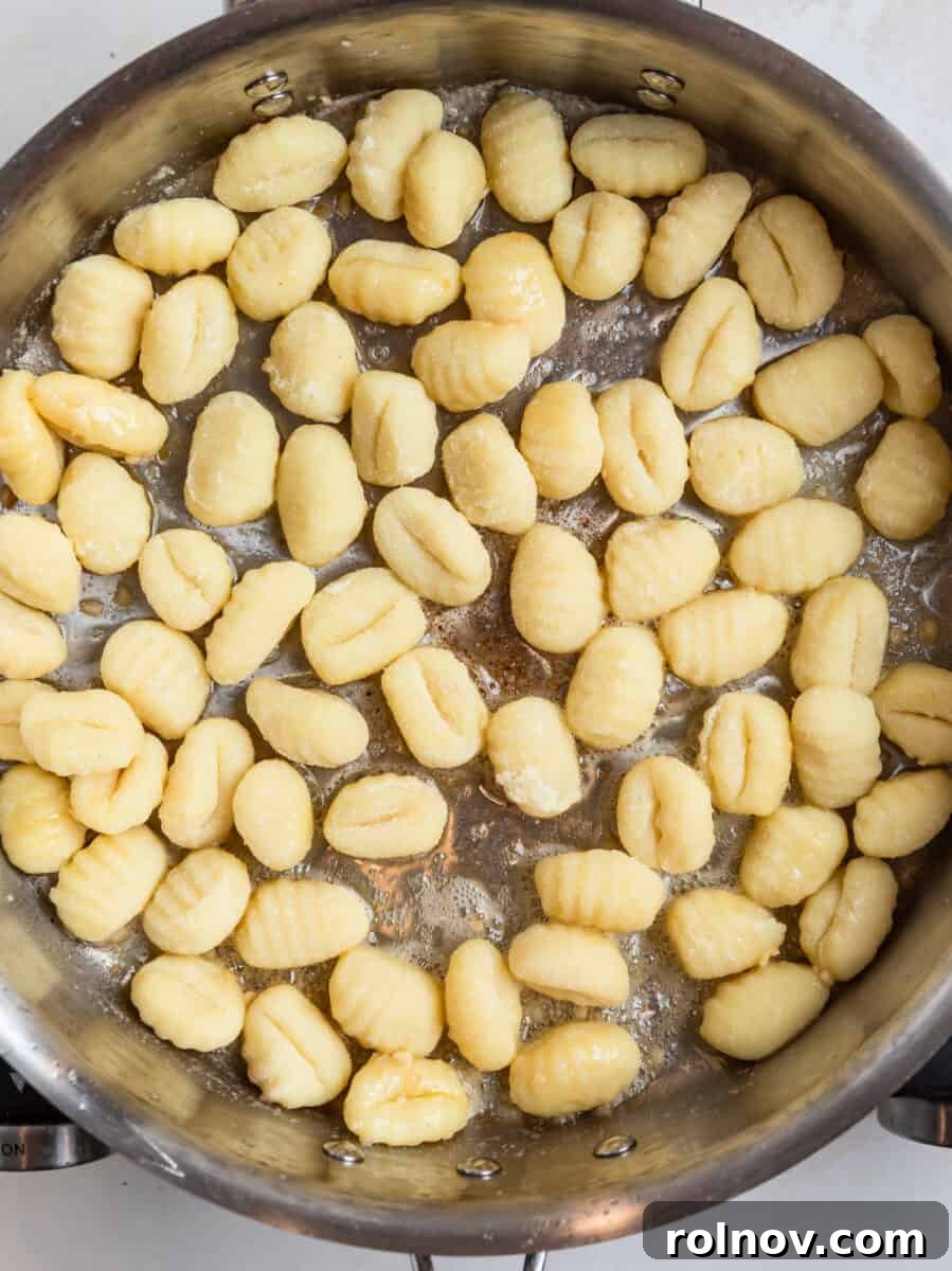 Golden Skillet Gnocchi 5 Uncooked gnocchi added to a skillet with butter and garlic, ready for pan-frying.