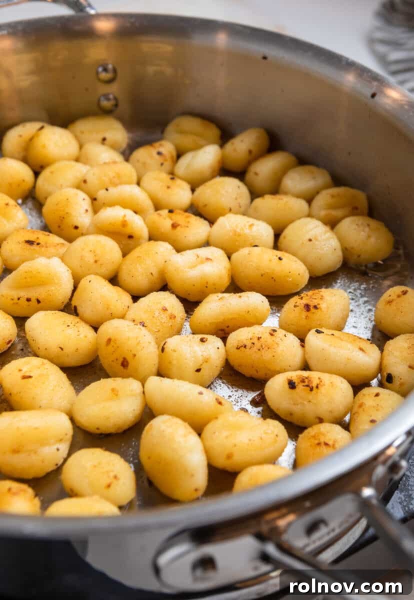 Golden Skillet Gnocchi 6 Gnocchi actively frying in a skillet, gradually turning golden brown as it crisps up.