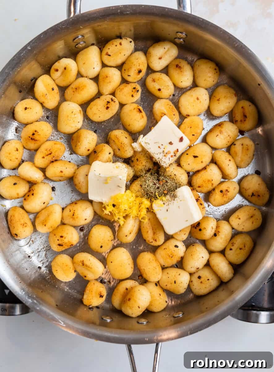 Golden Skillet Gnocchi 7 Butter, lemon zest, and Italian seasoning being added to a pan of perfectly fried gnocchi, ready for a flavorful toss.