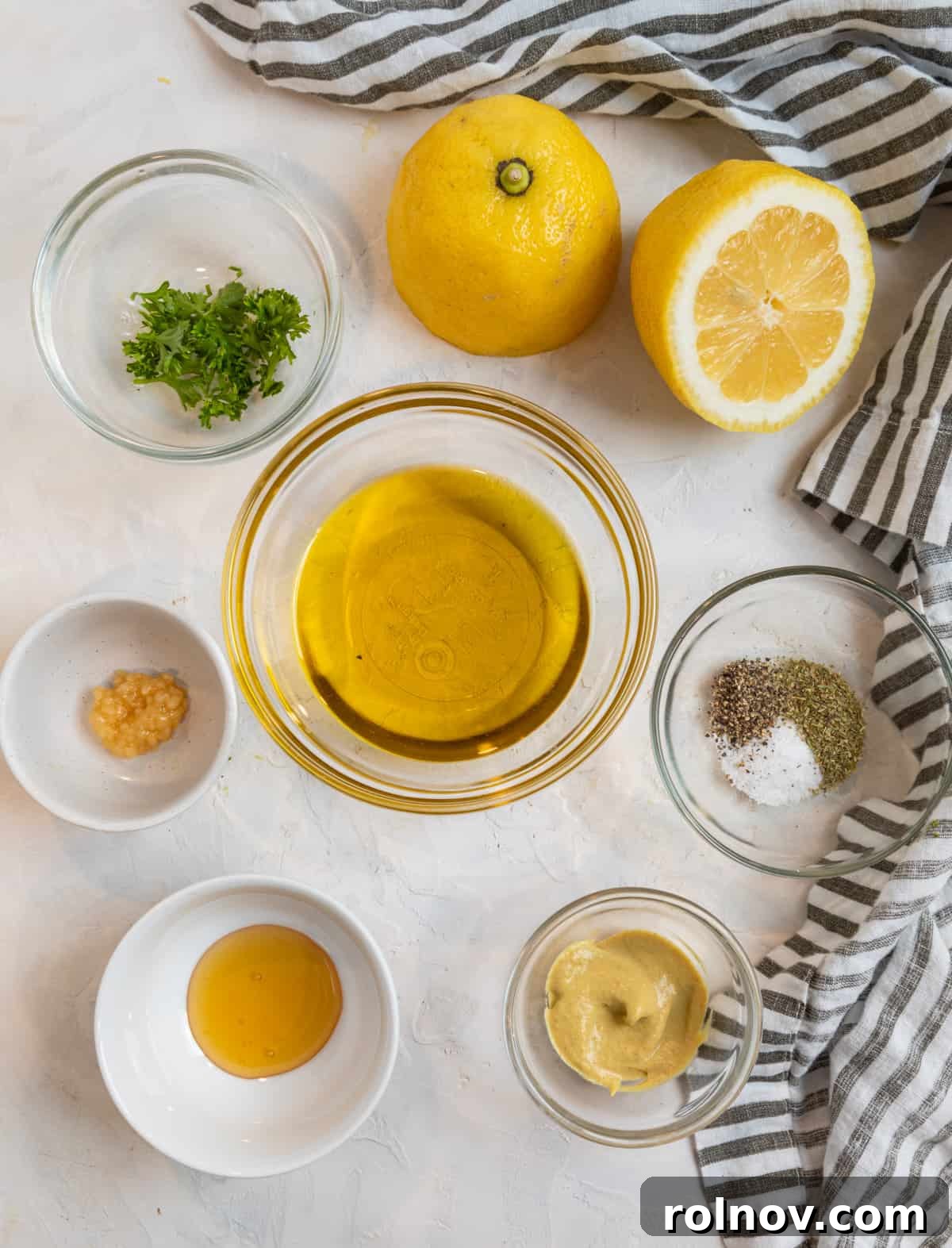 Lemon, olive oil, garlic, honey and other ingredients needed for recipe on counter.