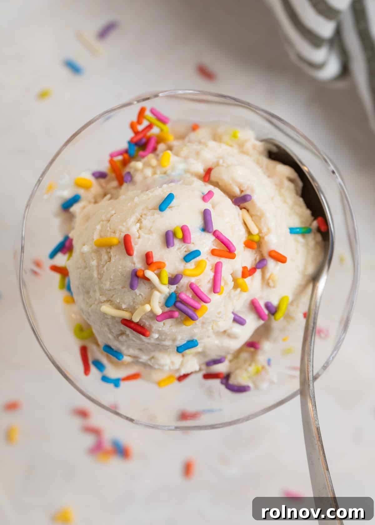 Cottage Cream Dream 2 Scooped cottage cheese ice cream in a glass dish with colorful sprinkles and a spoon digging in, highlighting its creamy texture.