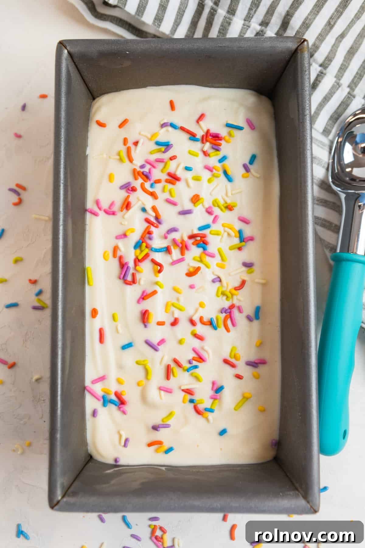 Cottage Cream Dream 11 Protein cottage cheese ice cream in a loaf pan, ready to be scooped, with an ice cream scoop and sprinkles.