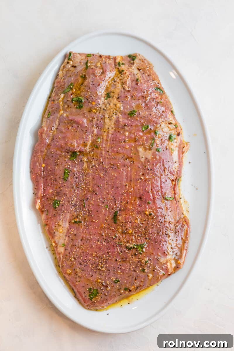 Powerhouse Flank Steak Salad 7 Marinated flank steak on a white plate, ready for grilling.