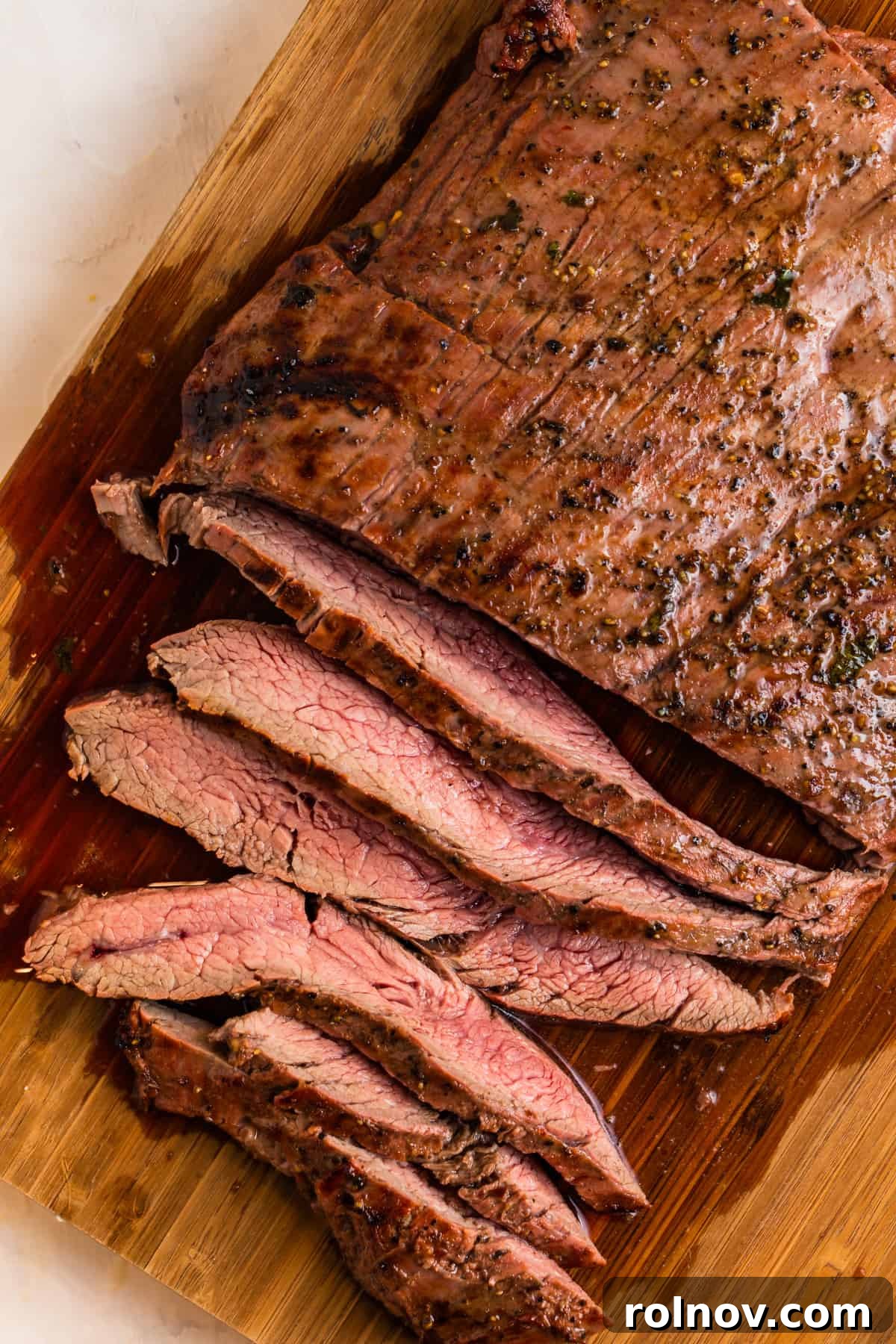 Powerhouse Flank Steak Salad 9 Thinly sliced grilled flank steak on a cutting board, showcasing its juicy interior.