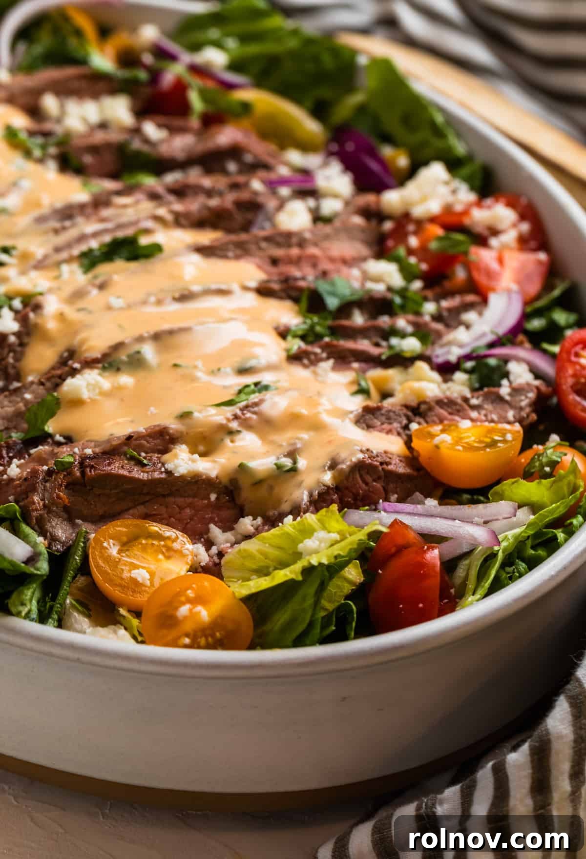 Powerhouse Flank Steak Salad 10 Sliced grilled steak arranged over lettuce greens, with spicy dressing drizzled on top.