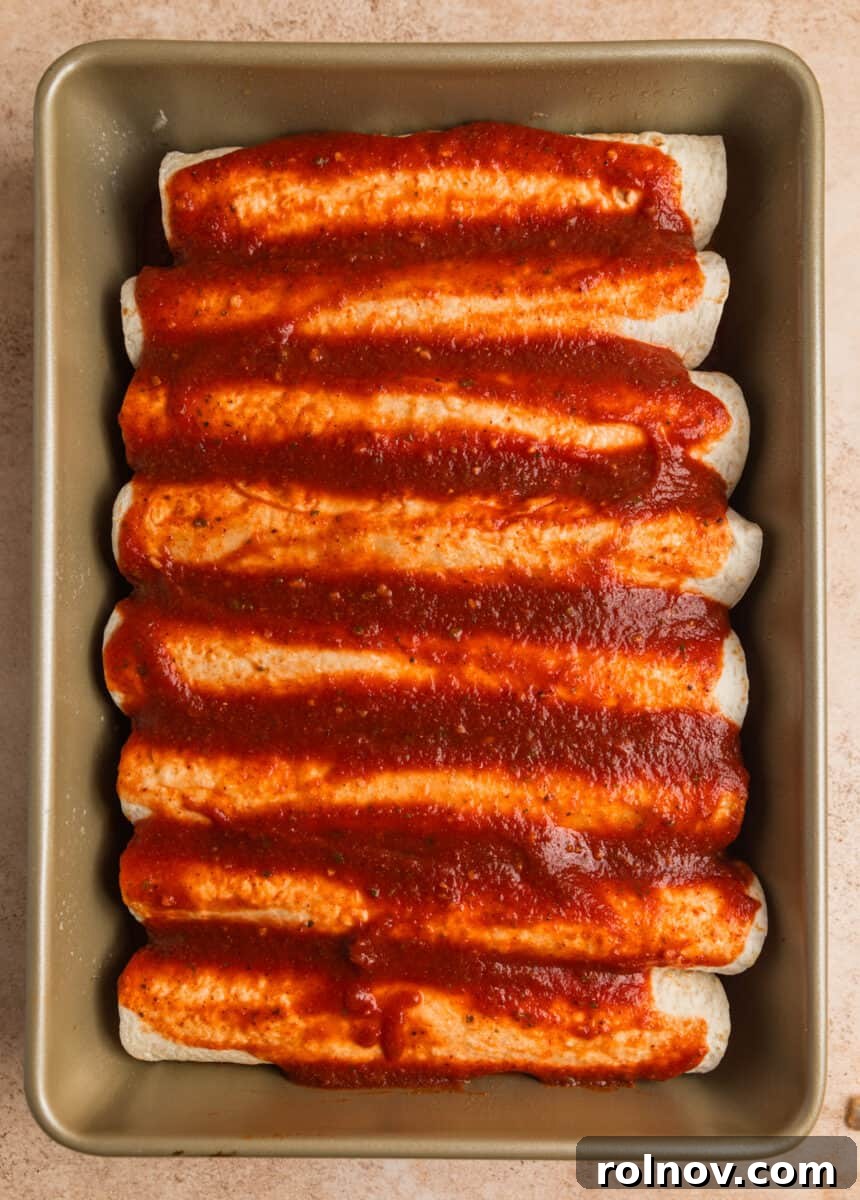 Enchilada sauce poured over prepped rolled tortillas.