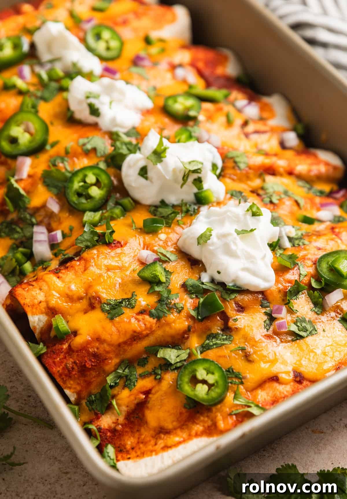Pan of enchiladas topped with sour cream and cilantro.