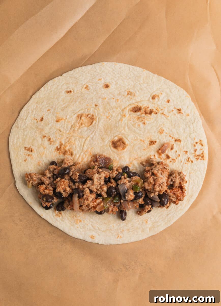 Ground turkey and black bean mixture spooned into tortilla.