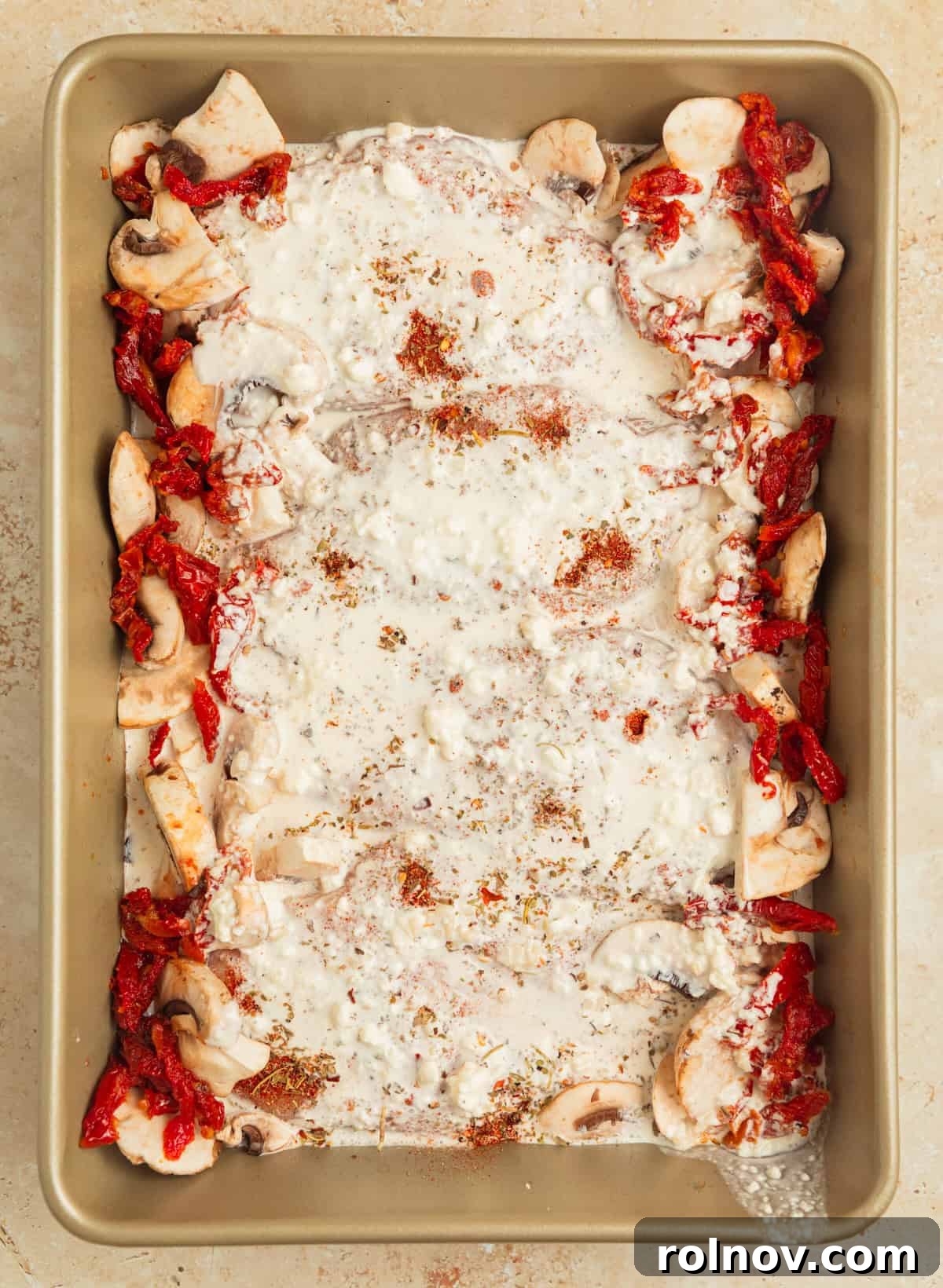 Savory Tuscan Chicken Bake 8 Cream sauce generously poured over the seasoned chicken, mushrooms, and sun-dried tomatoes in the baking pan, before entering the oven.