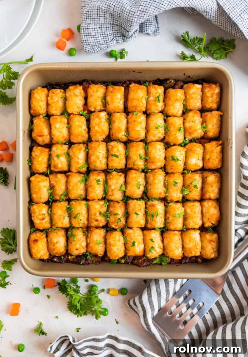 Baked tater tot shepherd's pie in pan with spatula and napkin beside.