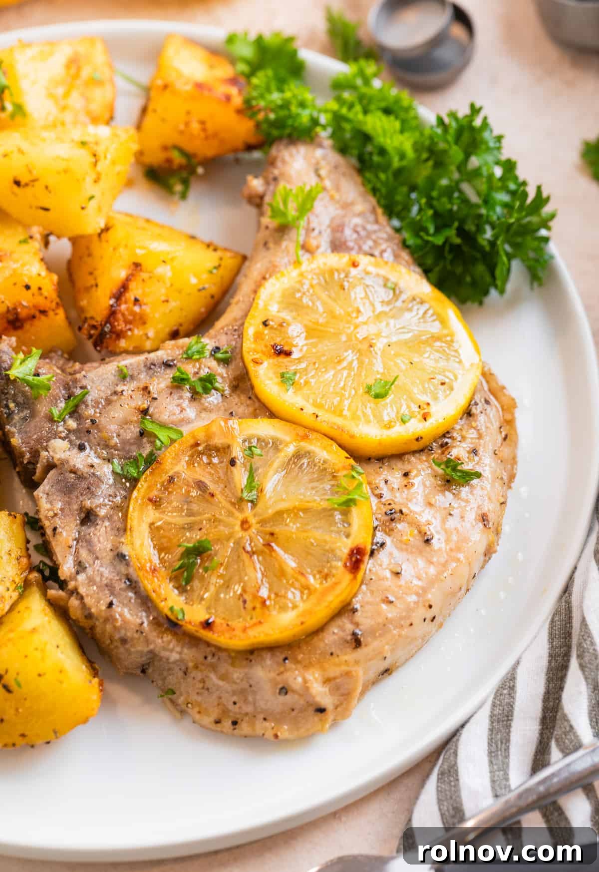 Zesty Lemon Pepper Pork Chops 8 A beautifully cooked lemon pepper pork chop on a white plate, adorned with vibrant lemon slices, showcasing its inviting presentation.