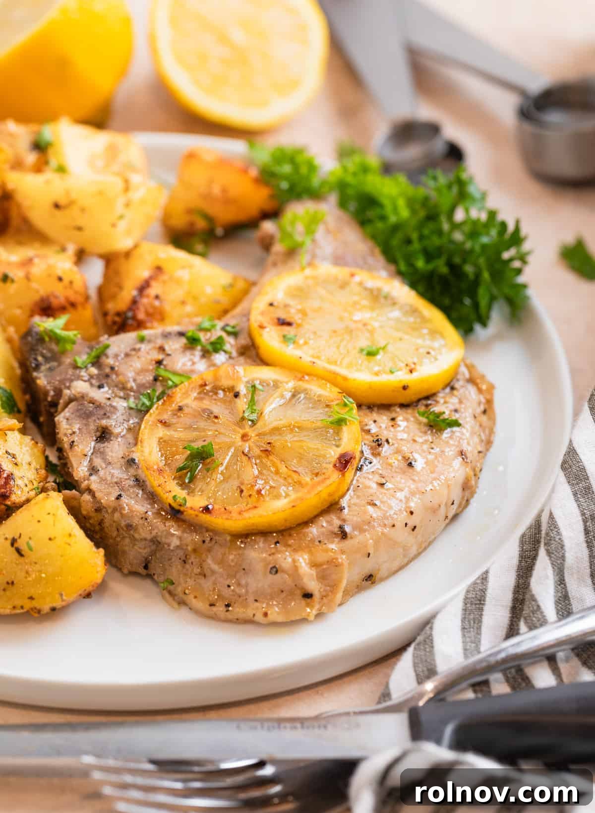 Zesty Lemon Pepper Pork Chops 9 A complete meal featuring a lemon pepper pork chop, roasted potatoes, and fresh parsley, elegantly presented on a white plate.
