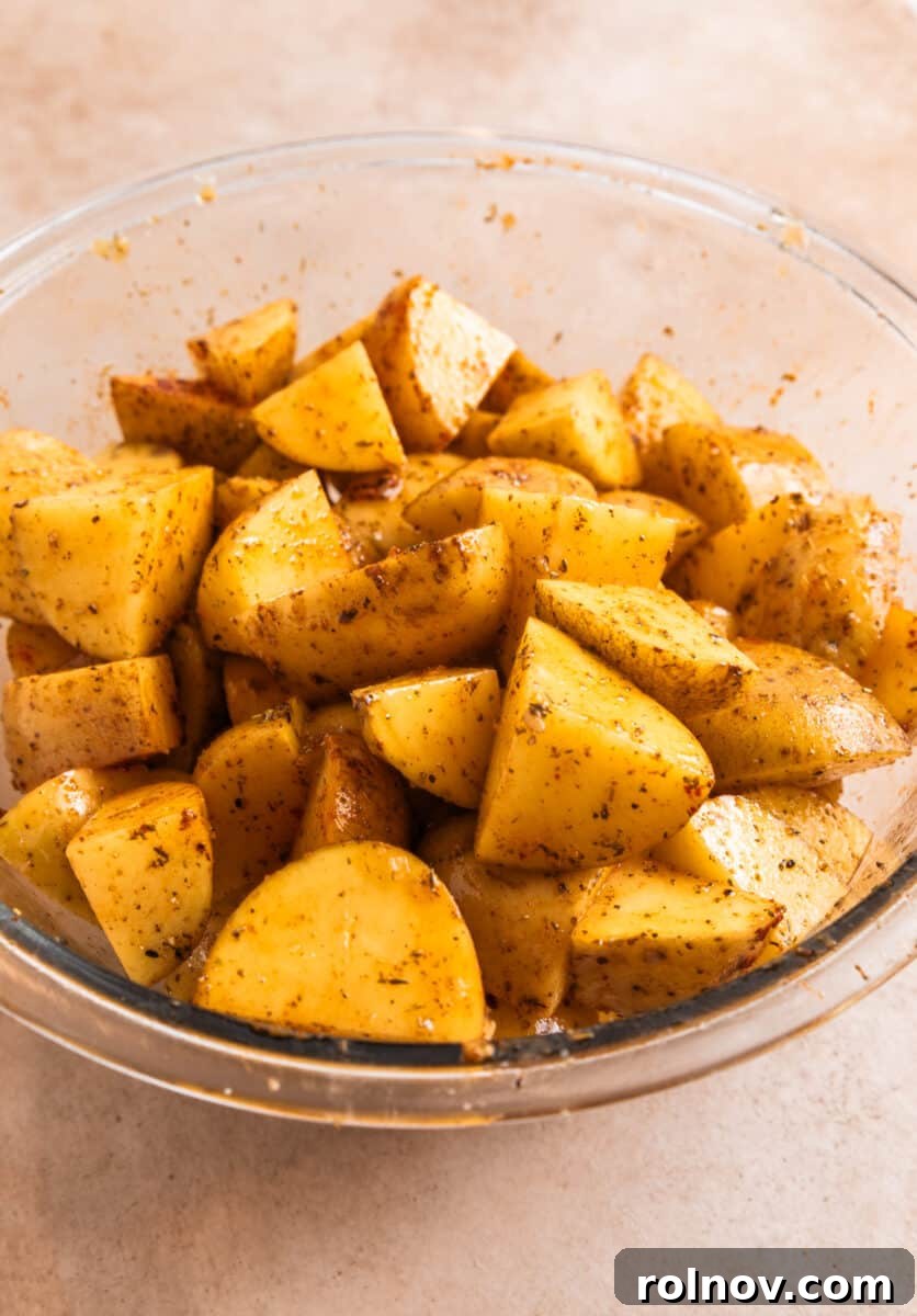Crispy Parmesan Roasted Potatoes 5 Potatoes in glass bowl tossed with olive oil and seasoning.