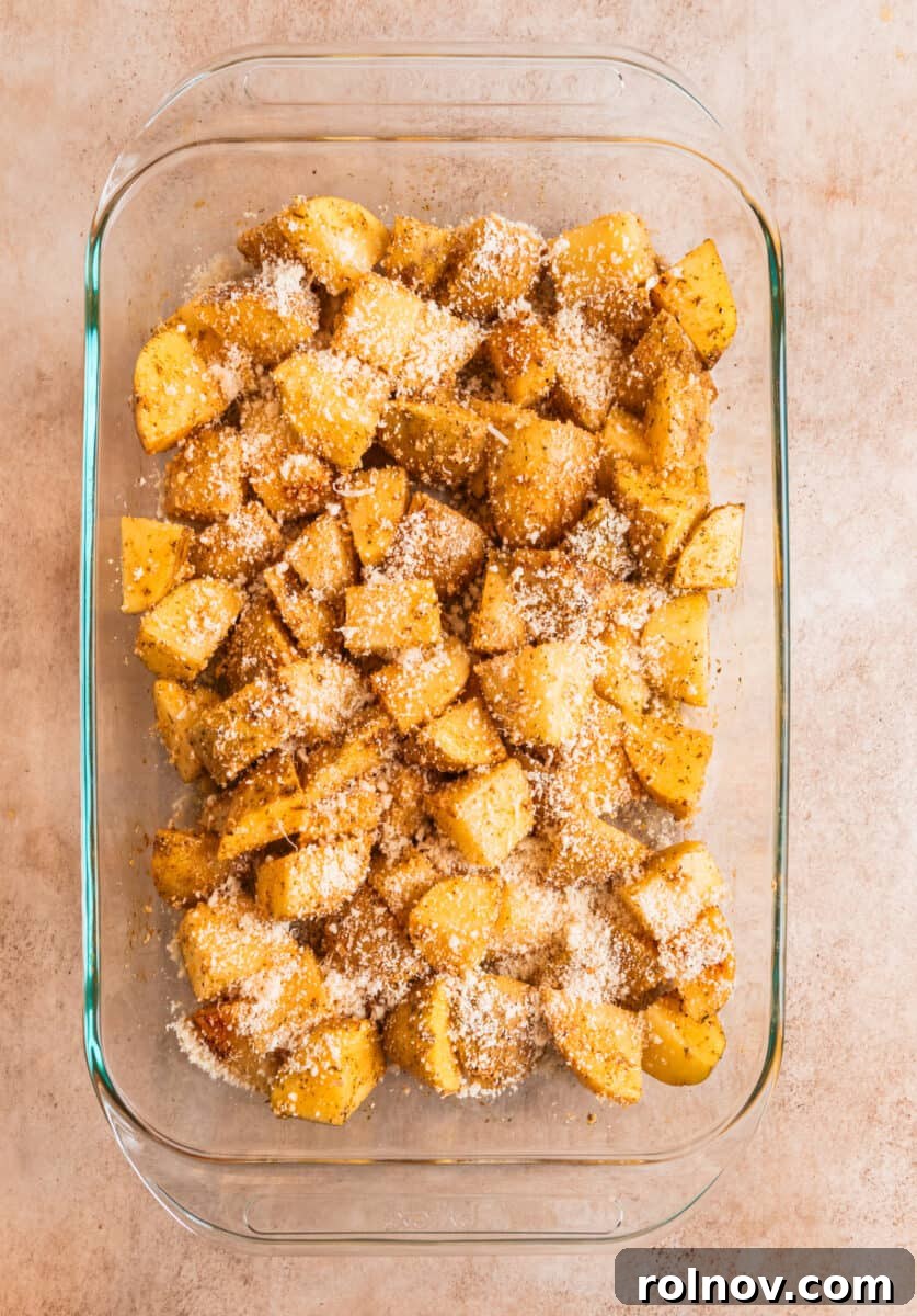 Crispy Parmesan Roasted Potatoes 6 Potatoes cubed in glass baking dish topped with grated parmesan.