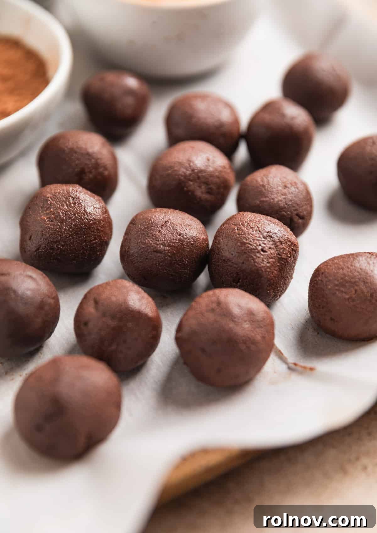 Effortless 5 Ingredient Amaretto Truffles 9 Chocolate truffles rolled and laying on parchment paper.