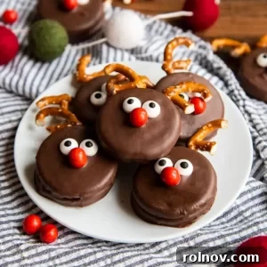 A white plate featuring cute chocolate-covered Oreos designed as reindeer with pretzel antlers and red noses.