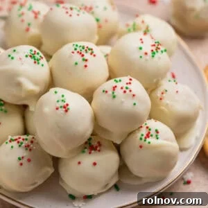 A plate of festive white chocolate-covered Christmas Golden Oreo Truffles topped with red, white, and green sprinkles.