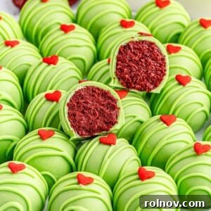 Red velvet Grinch Oreo balls displayed on a white plate, with a few having bites taken out.