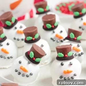 Oreo balls cleverly designed to resemble snowman heads with faces and festive hats on a white plate.