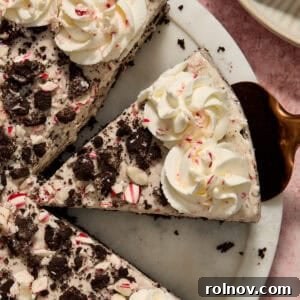 A slice of No Bake Peppermint Oreo Cheesecake on a spatula, showcasing its layers and festive appeal.