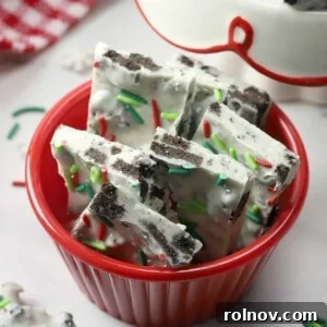 Oreo white chocolate peppermint bark in a red bowl, garnished with festive Christmas sprinkles.