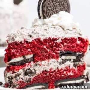 A perfect slice of Red Velvet Oreo Cake, showcasing layers of cake, Oreo buttercream, and whole Oreos.
