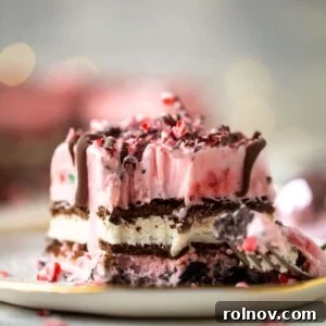 A layered holiday peppermint ice cream cake with a fork taking out a scoop.