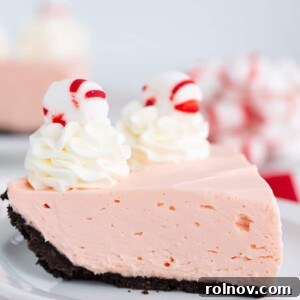 A festive slice of Candy Cane Pie with a chocolate cookie crust and crushed peppermints on top.