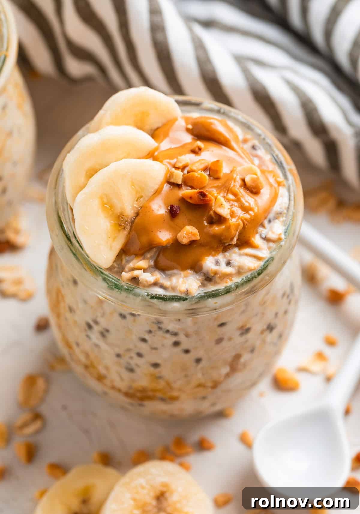 Power-Packed Overnight Oats 2 Peanut butter topped oatmeal in jar with sliced bananas and topped with chopped nuts, ready for a healthy breakfast.