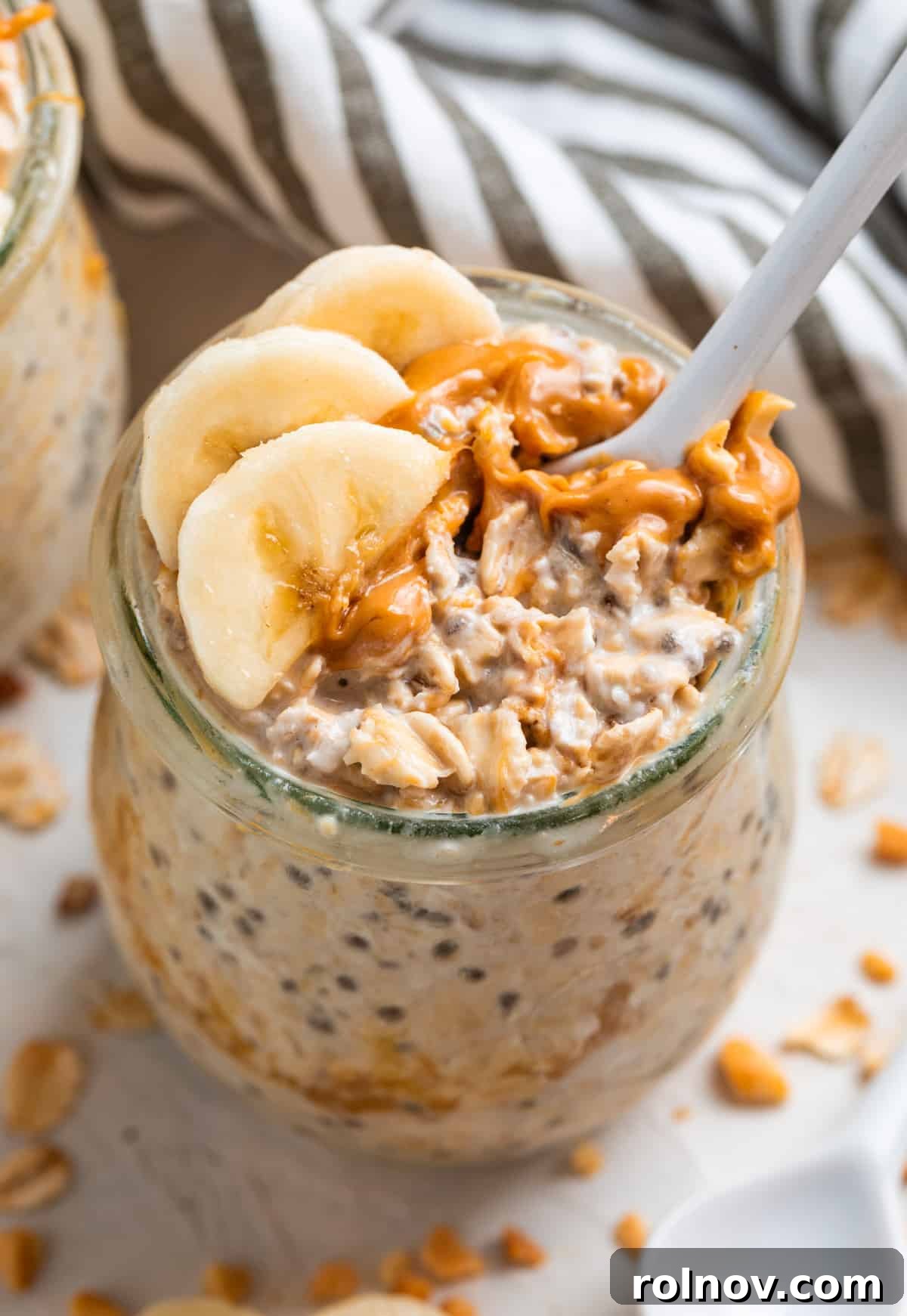 Power-Packed Overnight Oats 5 Spoon in jar of overnight oatmeal with peanut butter and banana, showcasing a healthy meal.