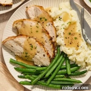 Slices of turkey breast on plate with mashed potatoes and green beans.