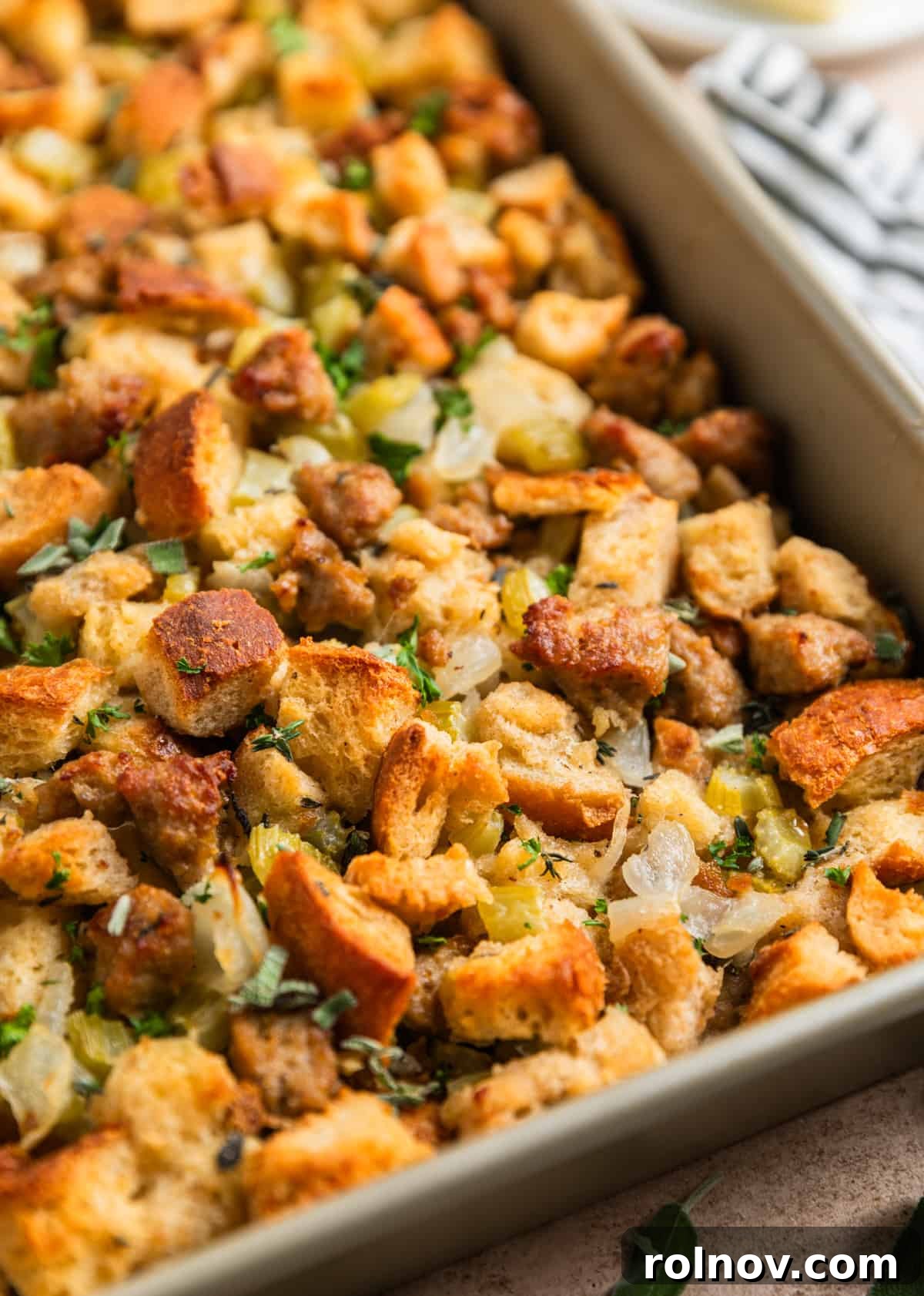 Classic Turkey Sausage Dressing 16 Baked turkey sausage stuffing in a pan, garnished with fresh herbs, ready for serving.
