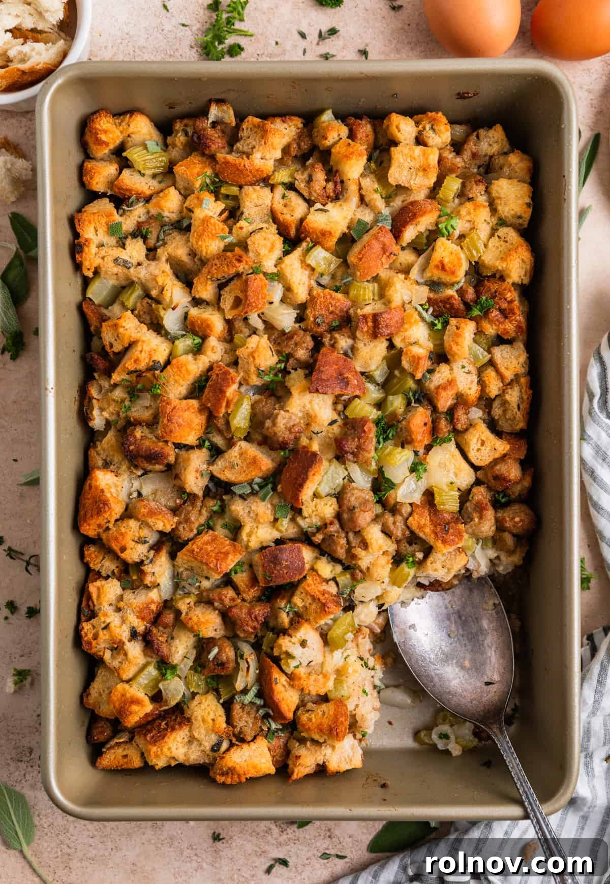 Classic Turkey Sausage Dressing 4 Overhead view of a baking pan filled with golden brown turkey sausage stuffing and a serving spoon scooping a portion.