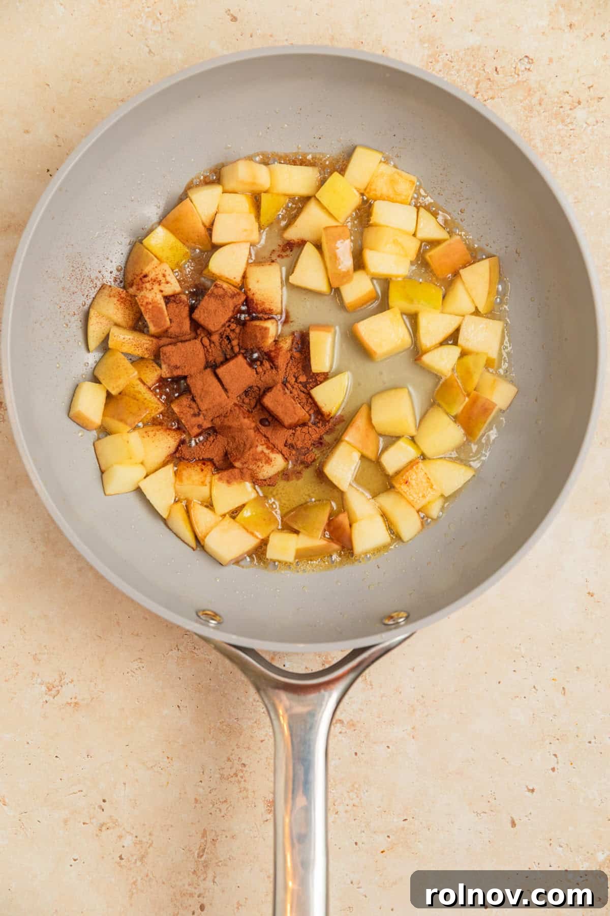 Apple Pie Overnight Oats 5 Softened apples simmering in a skillet with cinnamon, water, and maple syrup, creating a fragrant sauce.