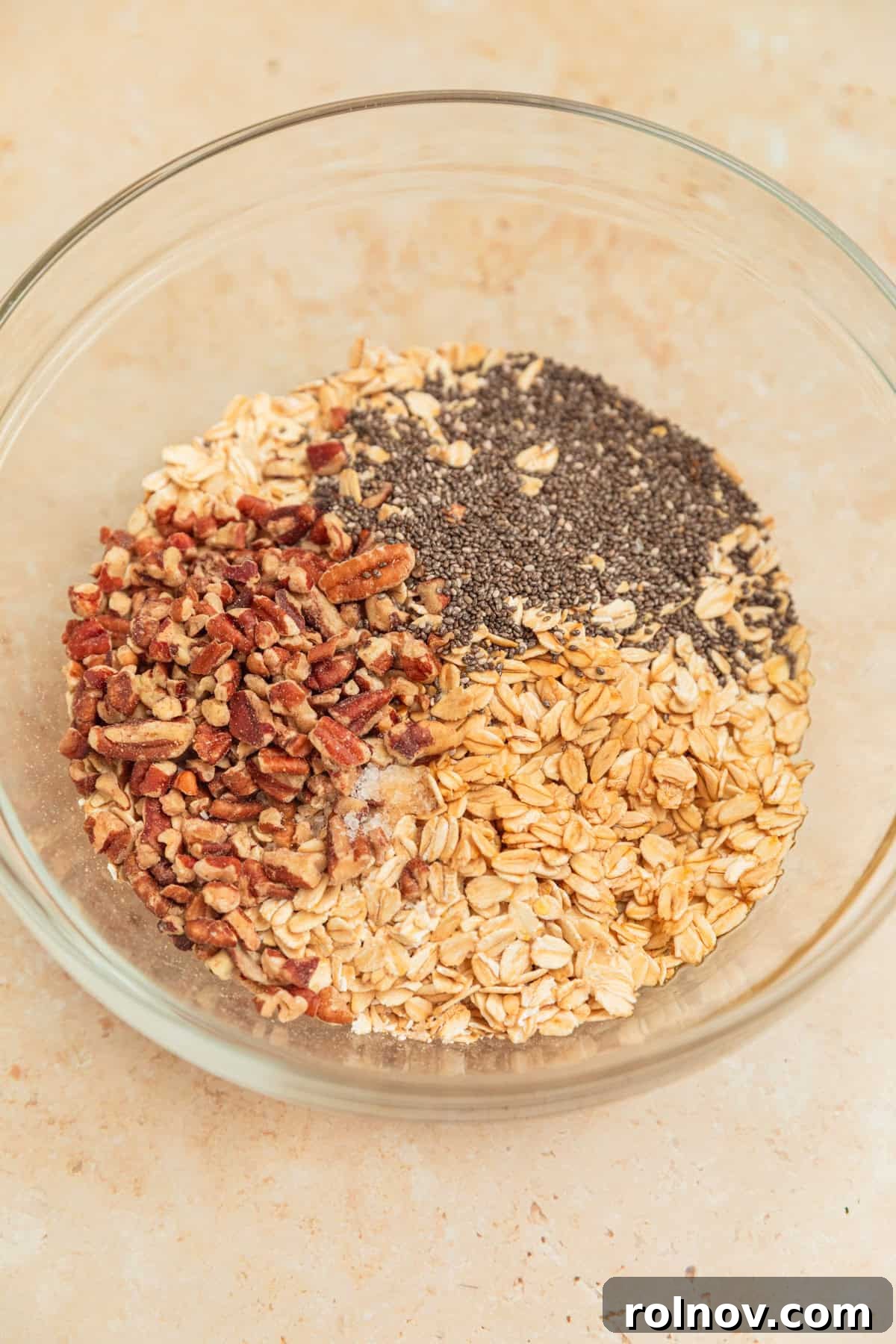 Apple Pie Overnight Oats 7 Rolled oats, chia seeds, chopped pecans, and other dry ingredients for overnight oats in a mixing bowl.
