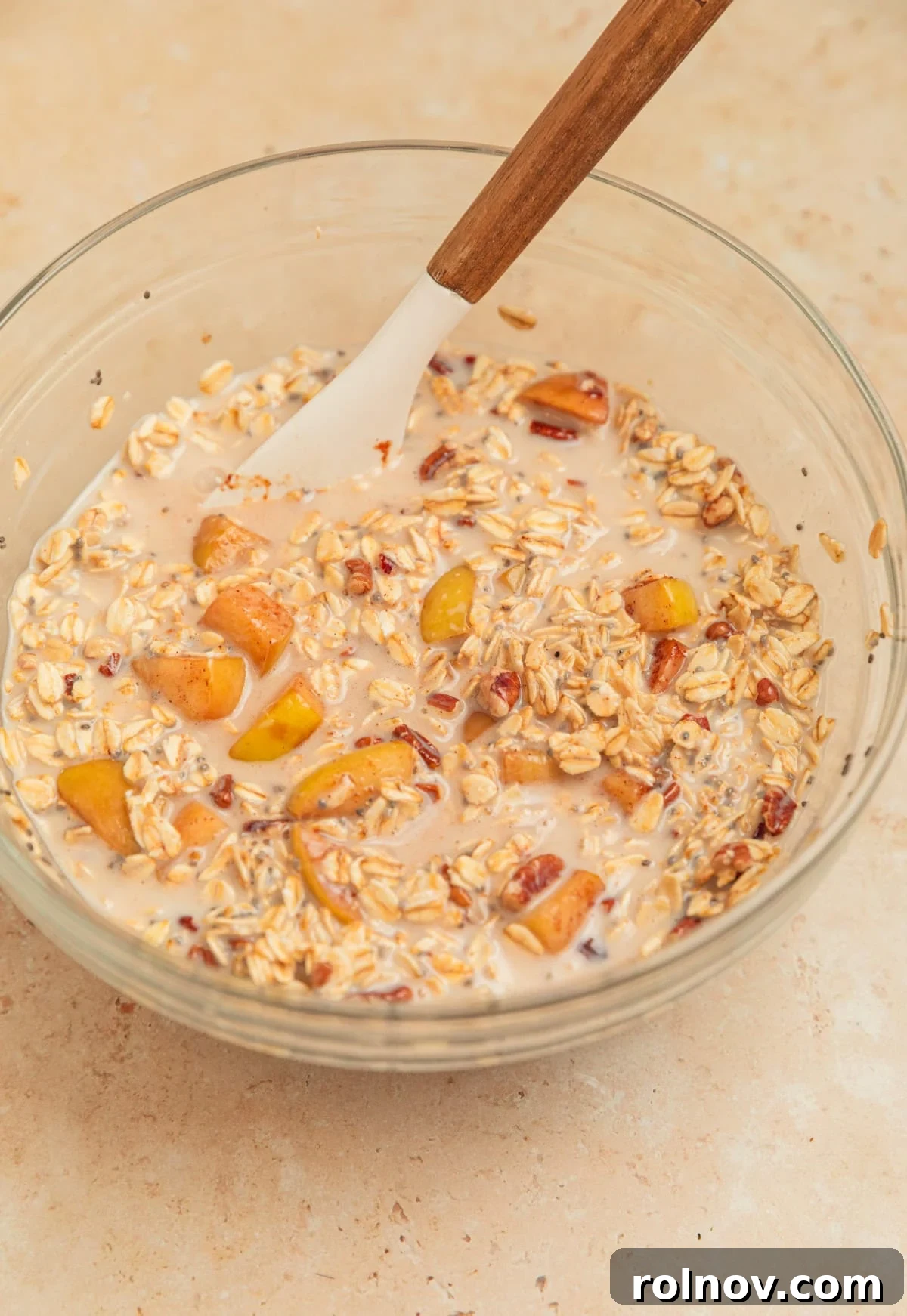 Apple Pie Overnight Oats 9 Apple overnight oatmeal mixture ready for chilling in a bowl with a spoon, showing its creamy texture.
