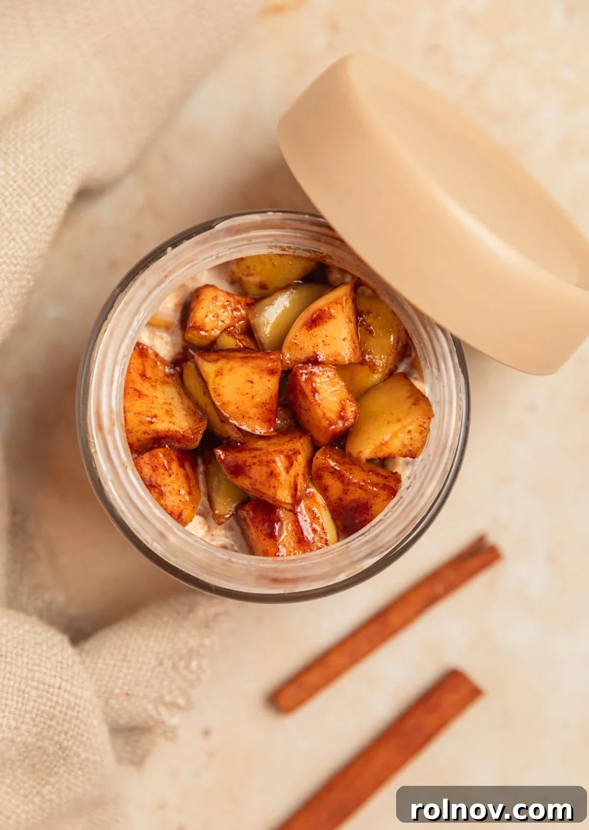 Apple Pie Overnight Oats 10 A glass jar filled with apple overnight oats, generously topped with the reserved cinnamon apples.