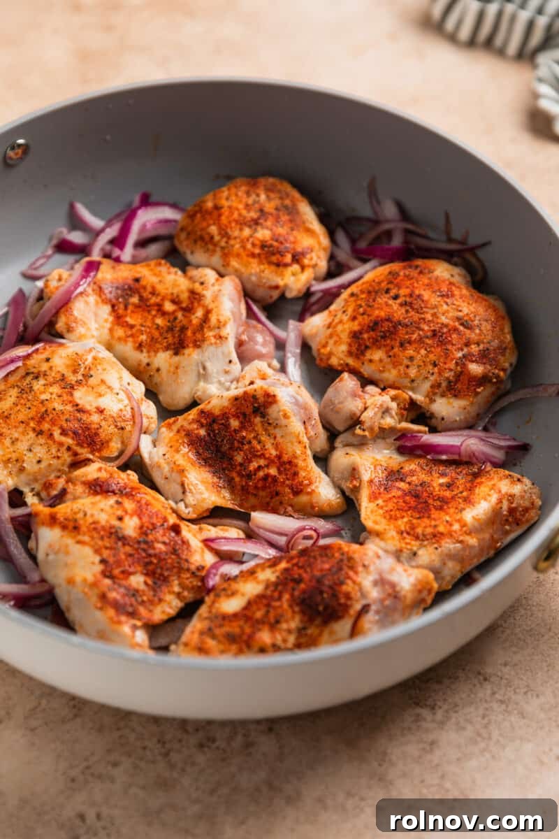 Sheet Pan Golden Chicken and Roasted Brussels Sprouts 5 Seared chicken thighs and red onion in skillet.